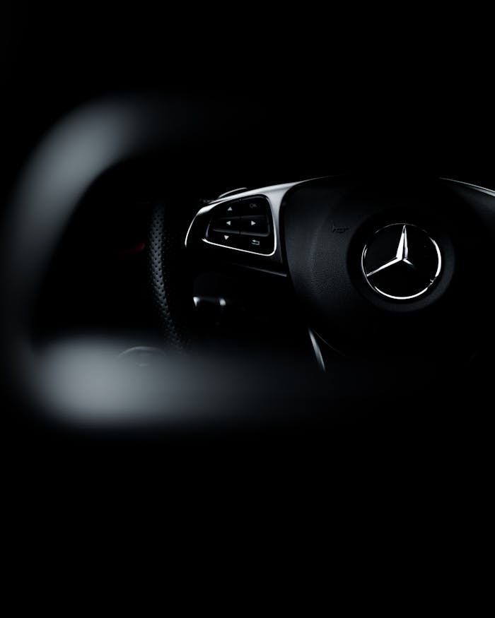 Dark, artistic shot highlighting a Mercedes-Benz steering wheel emphasizing luxury and design.